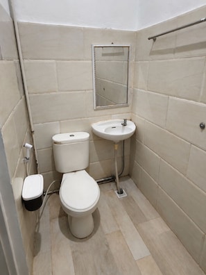 Et lille badeværelse med toilet, vask og spejl.