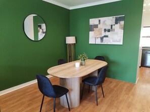A dining area with a round table, two chairs, a mirror, a lamp, and a painting on the wall. - Durbanville Work Home (Cape Town)