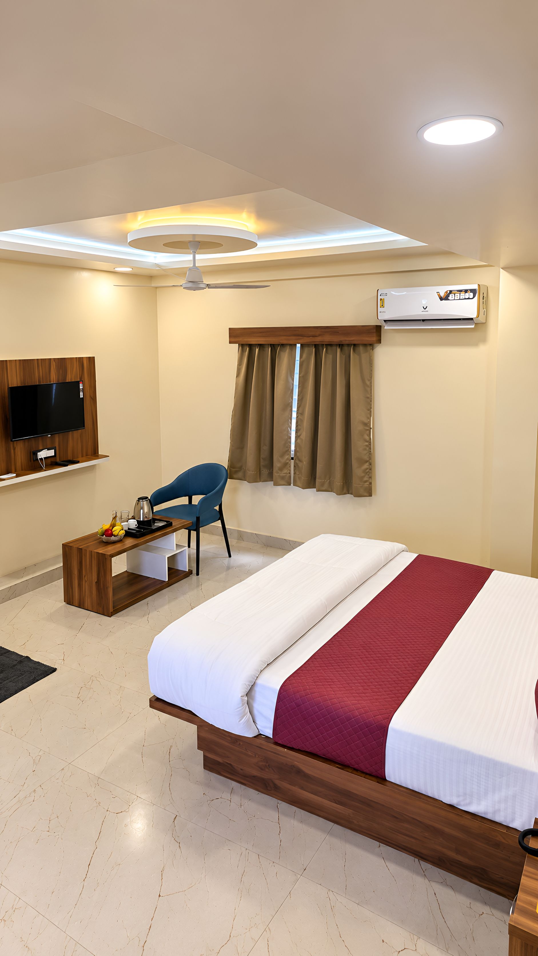 Ein Hotelzimmer mit einem Bett, einem Schreibtisch, einem Sessel, einem Fernseher und einer Klimaanlage.