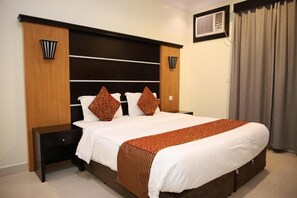 Habitación de hotel con una cama grande, una mesita de noche, un aire acondicionado montado en la pared y una ventana con cortinas.