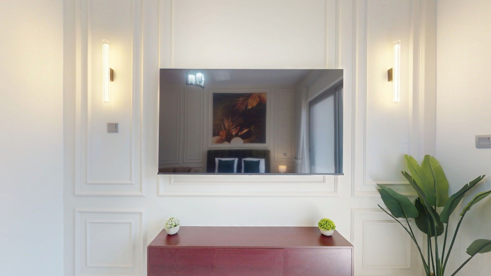 A room with a large mirror, a red cabinet, and two wall-mounted lights.