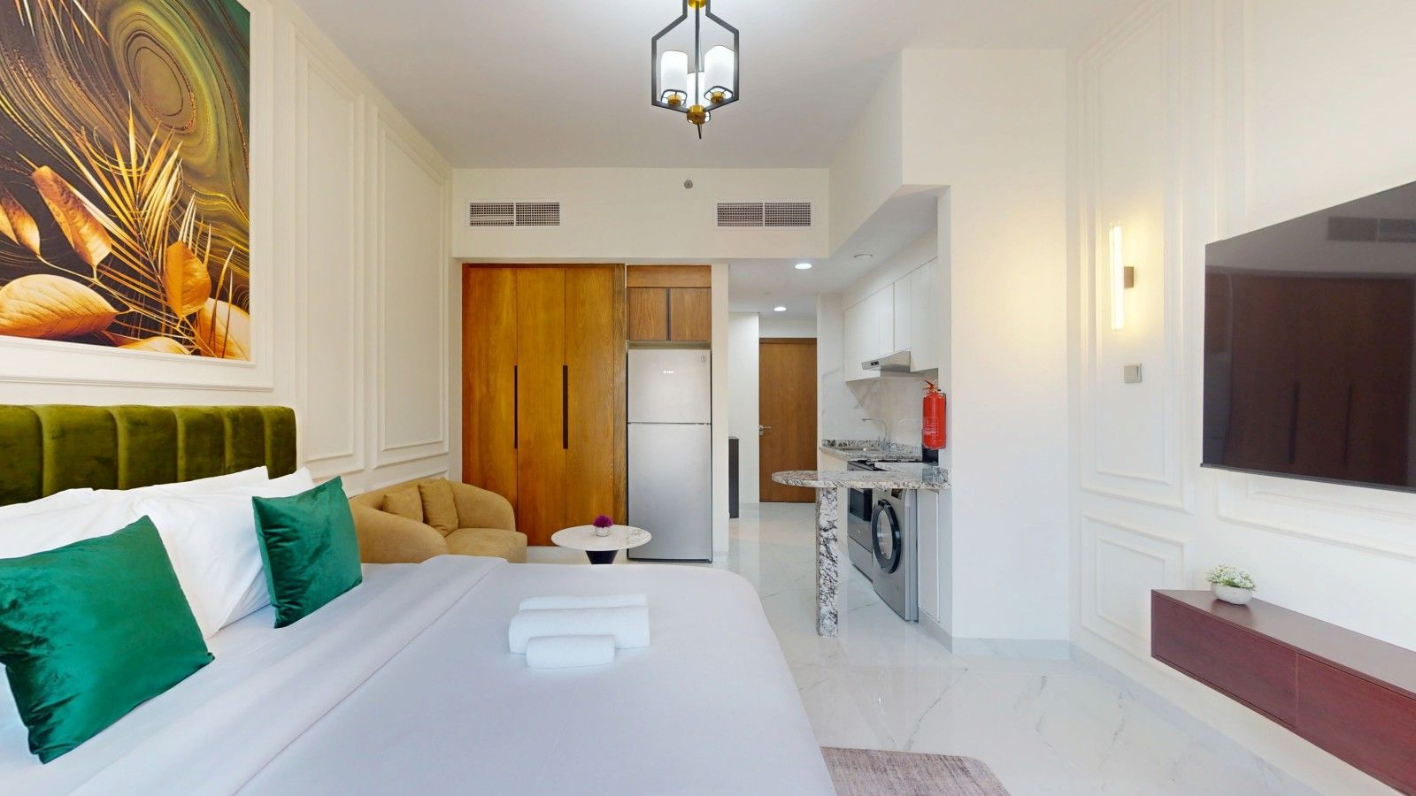 A hotel room with a bed, a sofa, a dining area, and a TV.