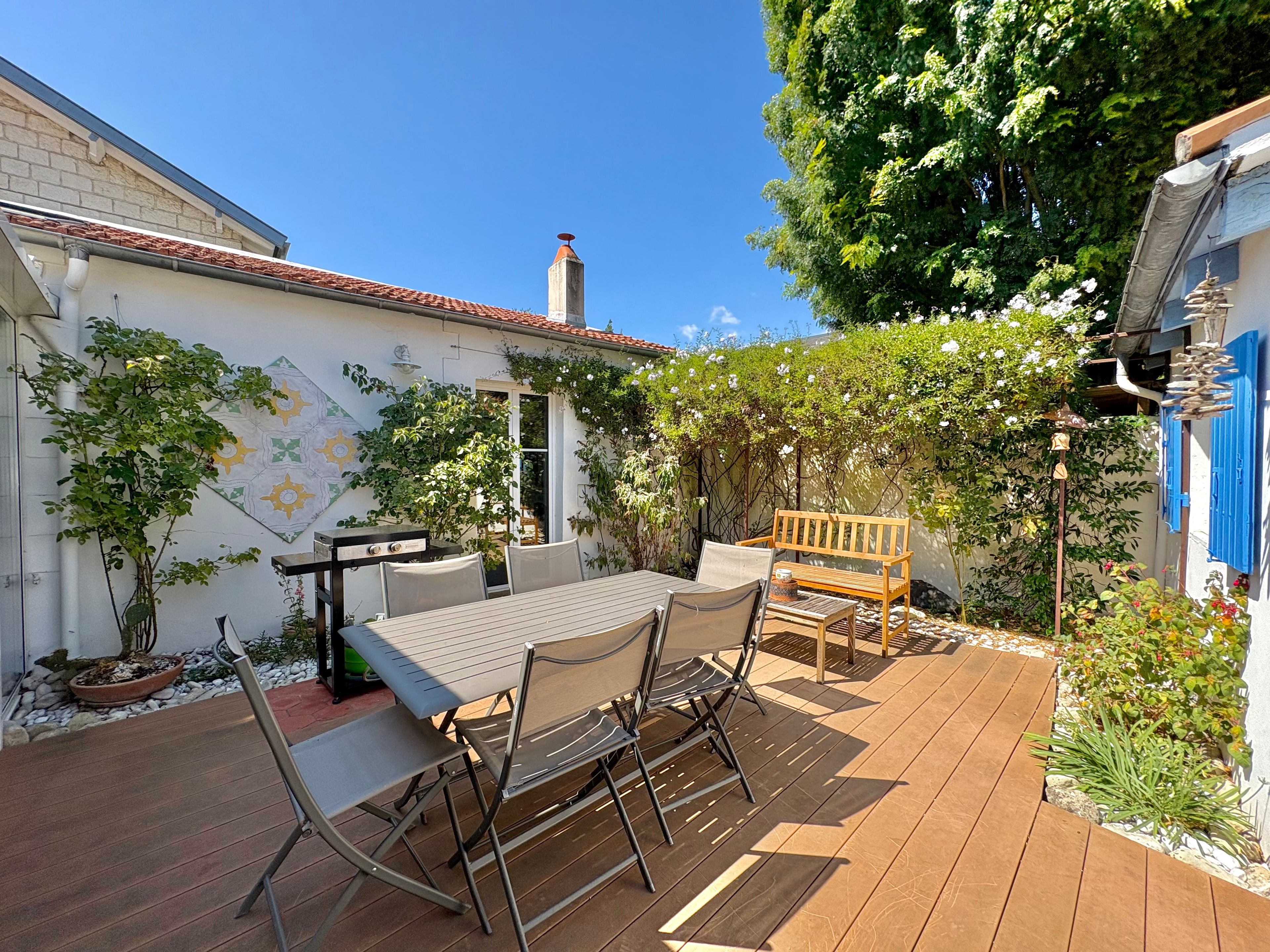 A patio with a table and chairs, surrounded by plants and a mural.