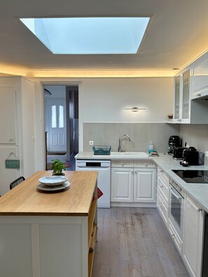 Una cocina moderna con tragaluz, armarios blancos y una mesa de comedor de madera.