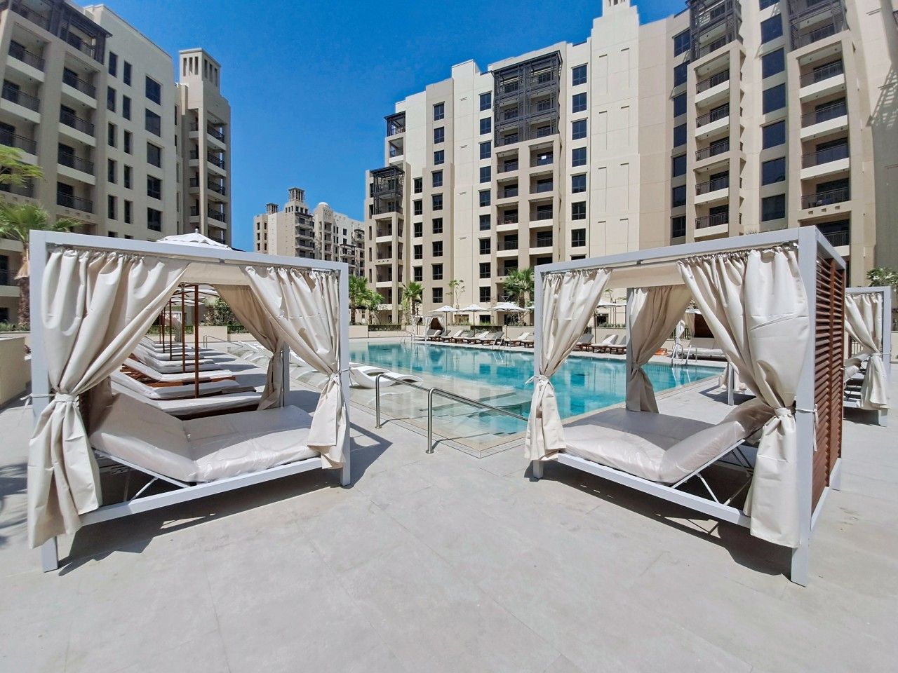 A rooftop pool area with two sunbeds and a swimming pool.