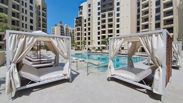 A rooftop pool area with two sunbeds and a swimming pool.