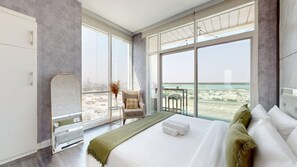 Une chambre d’hôtel moderne avec un grand lit, une chaise, une petite table et une vue sur la plage.