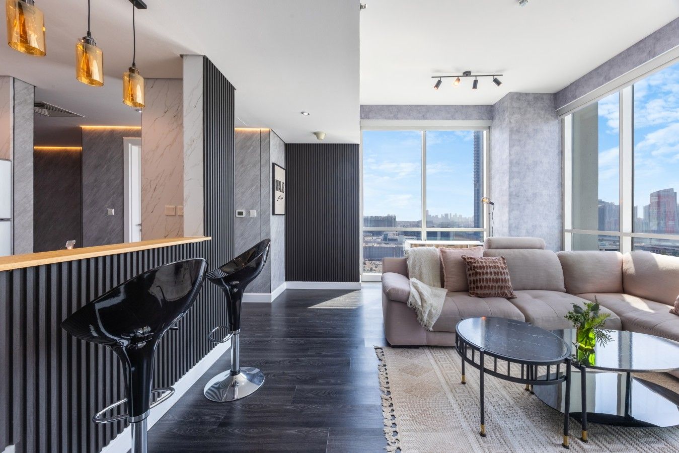 A modern living room with a large window, a sofa, a coffee table, and a dining area with chairs.