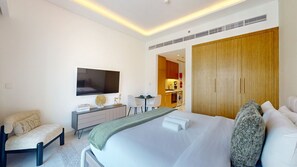 Una habitación de hotel con cama, escritorio, silla, televisor y armario.