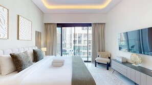 Habitación de hotel moderna con una cama grande, zona de estar, televisión y vistas a la ciudad.