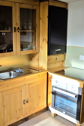 Une cuisine avec des meubles de rangement en bois, un évier, une cuisinière et un réfrigérateur.