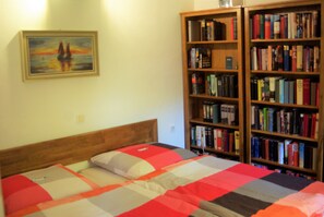 Une chambre à coucher avec un lit, une bibliothèque et un tableau accroché au mur.