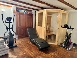 A home gym with exercise equipment, a wooden cabinet, and a curved bench. - New Listing (Camucia)