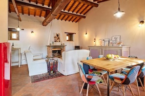 A cozy living room with a fireplace, a dining table, and a sofa. - New Listing (Camucia)