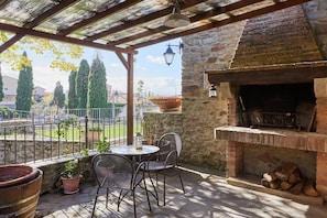 An outdoor patio with a brick fireplace, a round table, and chairs. - New Listing (Camucia)