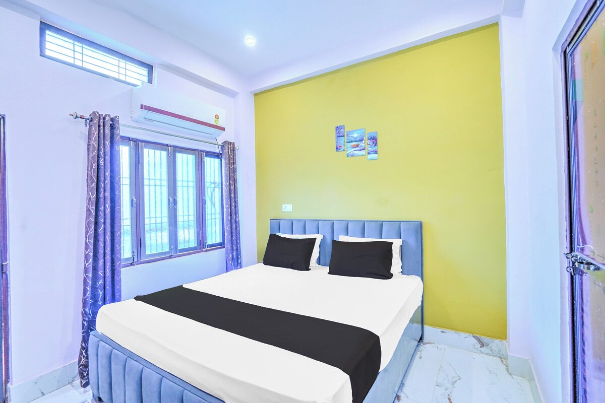 Une chambre à coucher avec un lit, des rideaux, une fenêtre et un climatiseur fixé au mur.