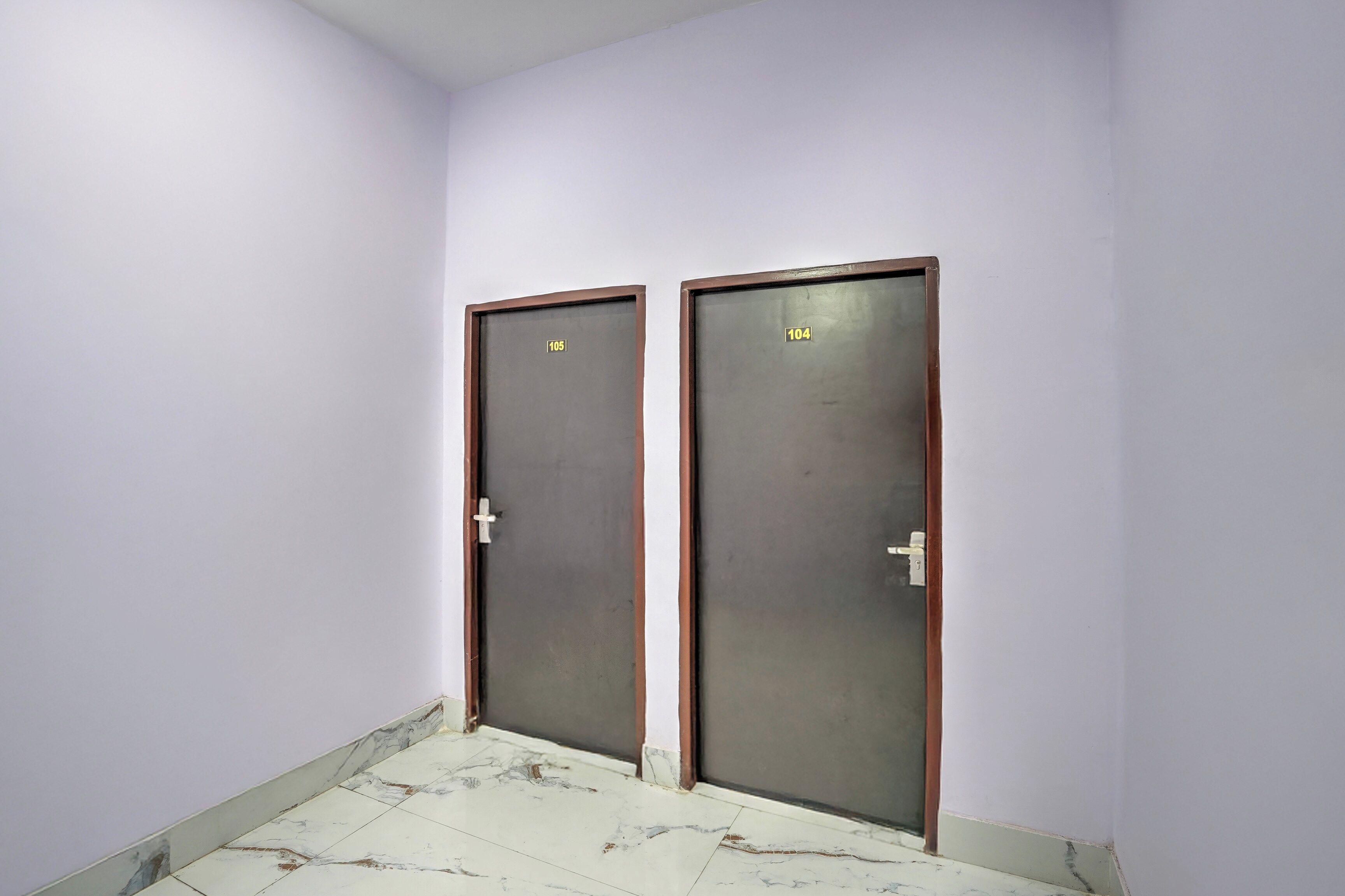 Dos puertas con los números 105 y 104, un suelo de baldosas y una pared lisa.
