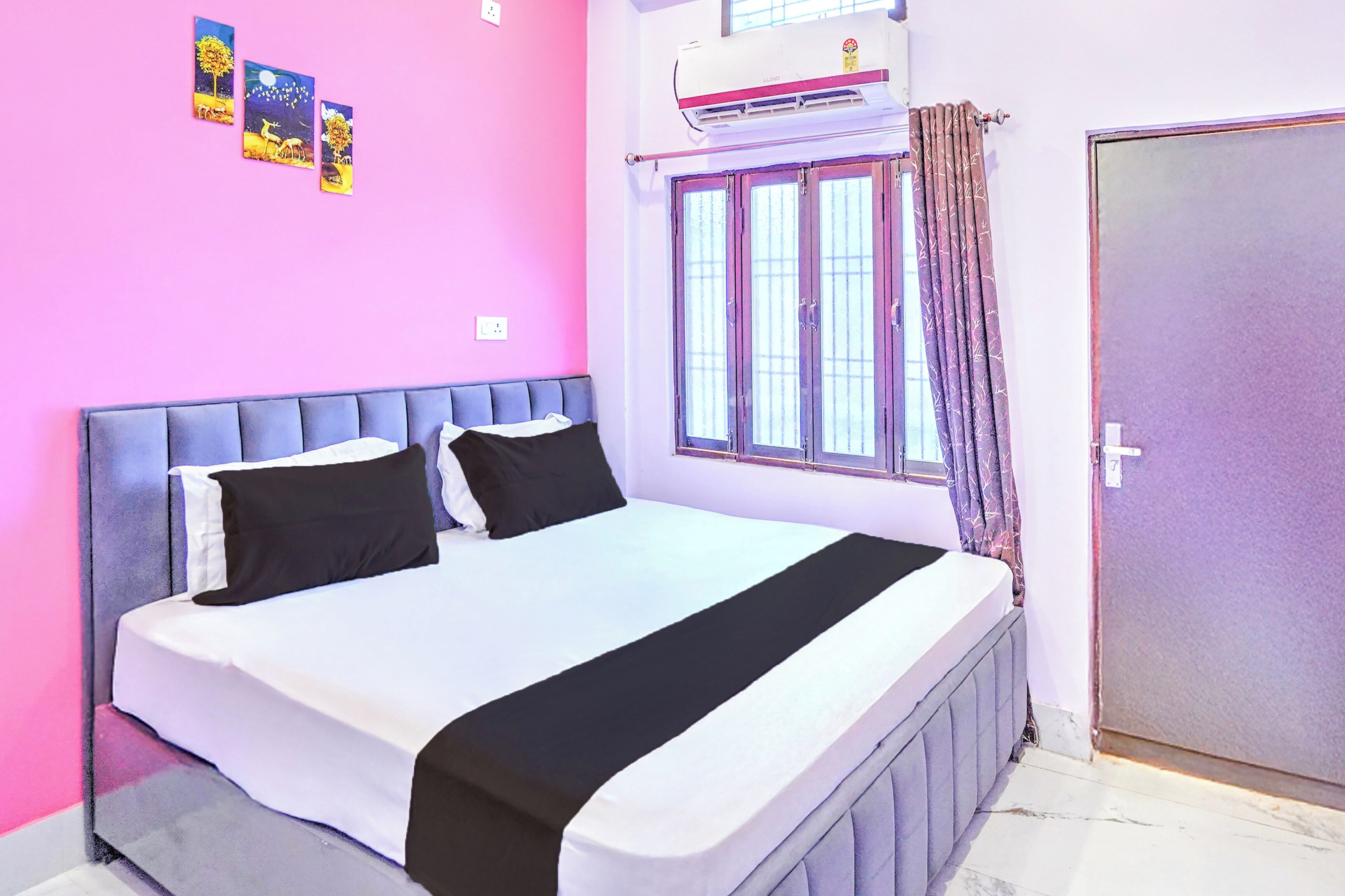 A bedroom with a bed, a window with curtains, and an air conditioning unit.