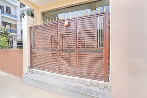 Una entrada cerrada con un portón metálico, una ventana con rejas y una valla decorativa.
