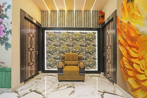 Una habitación con sofá, un papel tapiz estampado y un cuadro grande.