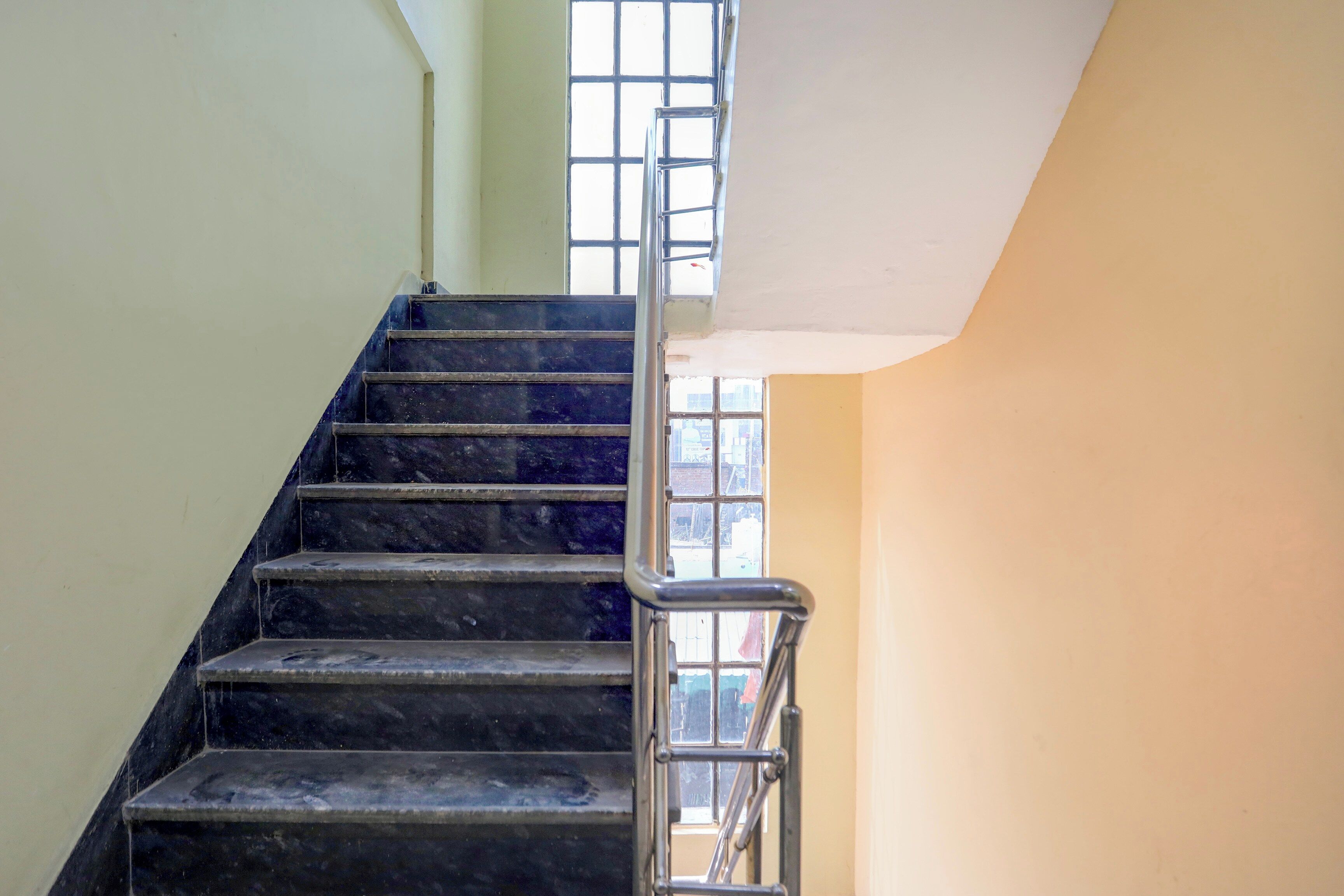 A staircase with metal handrails, leading to a landing with a window.