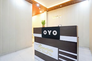 Una mesa de recepción con un letrero que dice 'OYO' y otro letrero debajo que indica 'Banaras Guest House'.