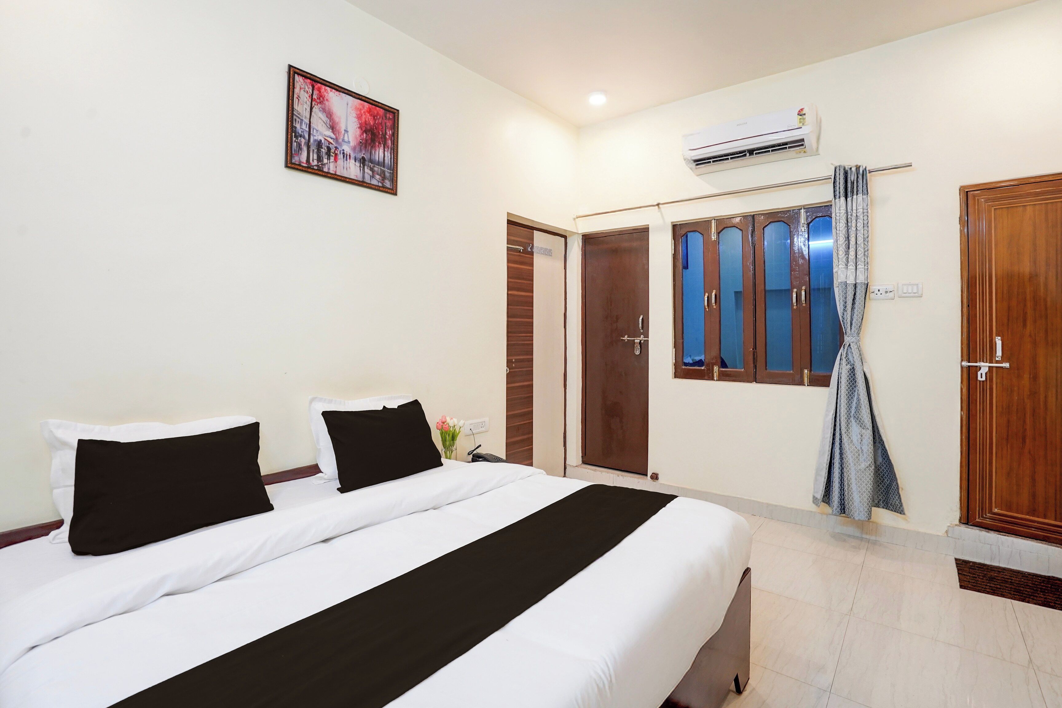 Une chambre d’hôtel avec un lit, un tableau, un appareil de climatisation et une armoire.