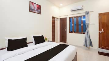 Une chambre d’hôtel avec un lit, un tableau, un appareil de climatisation et une armoire.