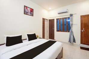 Une chambre d’hôtel avec un lit, un tableau, un appareil de climatisation et une armoire.