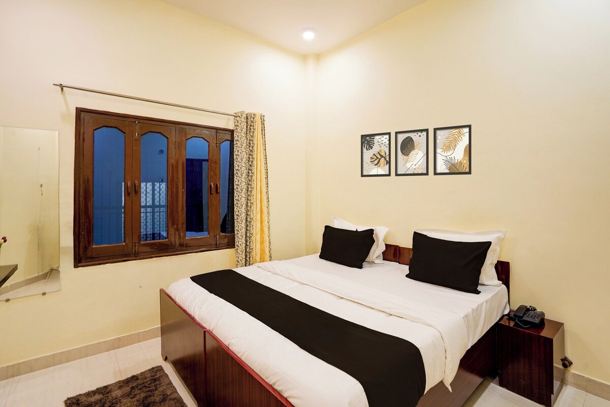 Une chambre à coucher avec un lit, une table de chevet, un téléphone et une fenêtre avec des rideaux.