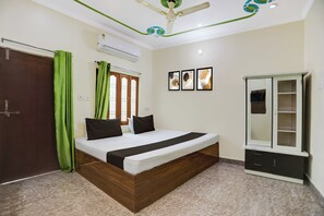 Een slaapkamer met een bed, een kledingkast, een plafondventilator en een wandairconditioner.