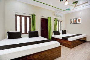 Ein Hotelzimmer mit zwei Betten, jeweils mit einer schwarz-weißen Tagesdecke, grünen Vorhängen und einem Holz-Kopfteil.
