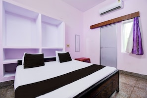 Une chambre d’hôtel avec un lit, une armoire, une petite table et une fenêtre avec des rideaux.