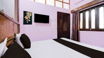 A room with a bed, a flat-screen TV, a door, and a window with curtains.