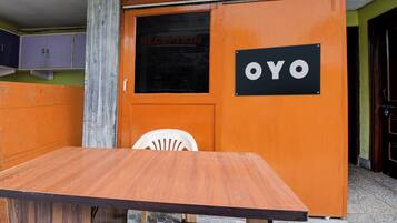 Un área de recepción con una mesa de madera y una silla blanca. Un letrero con las letras 'OYO' es visible en la pared.