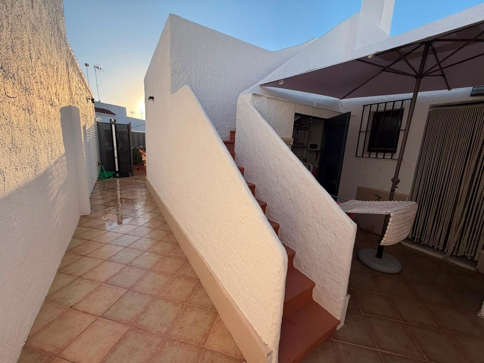Una escalera conduce a un espacio exterior cubierto con piso de baldosas.