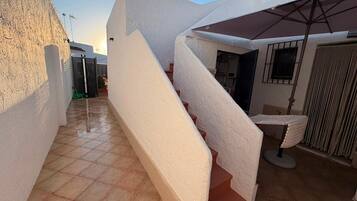 Una escalera conduce a un espacio exterior cubierto con piso de baldosas.