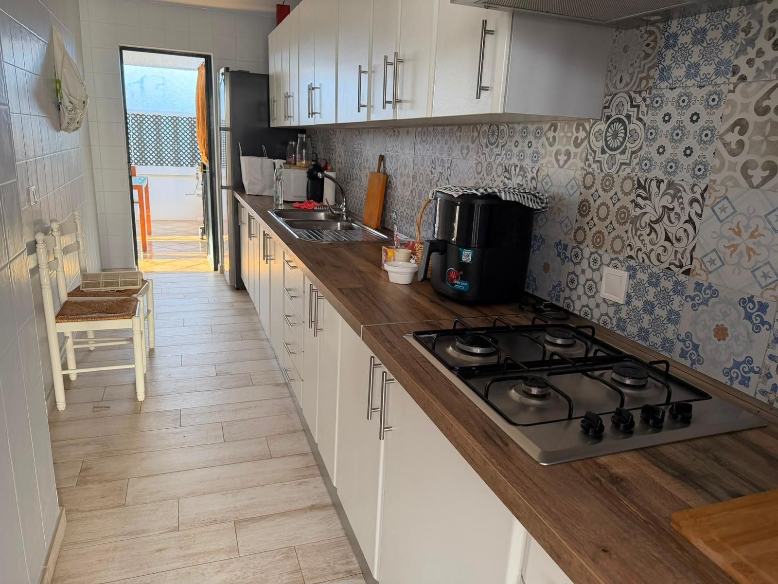 Una cocina con estufa a gas, armarios blancos y salpicadero decorado.
