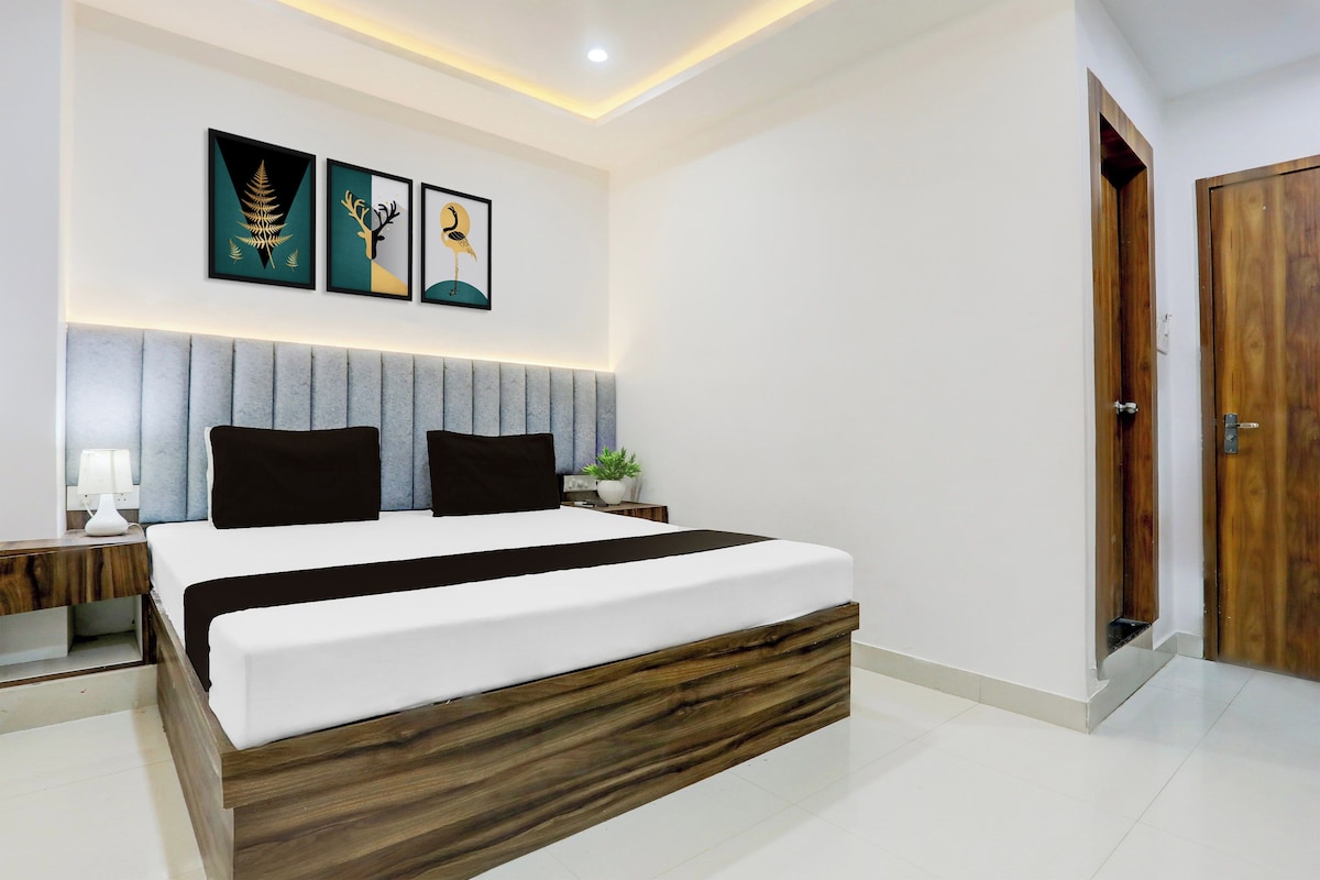 A modern bedroom with a bed, bedside tables, a nightstand, a wall-mounted lamp, and framed artwork.