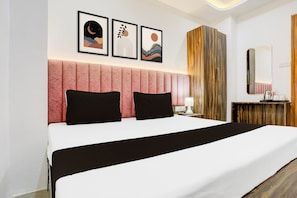 A hotel room with a bed, a nightstand, a mirror, and artwork on the wall. - Hotel O Natraj Paying guest house (Varanasi)
