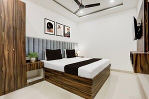A modern bedroom with a bed, bedside tables, a ceiling fan, and artwork on the wall. - Hotel O Natraj Paying guest house (Varanasi)