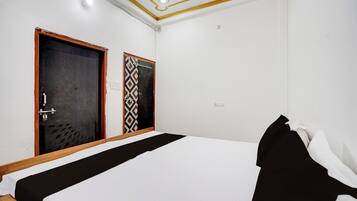 Une chambre d’hôtel avec un lit simple, une armoire et une porte ornée d’un motif décoratif.