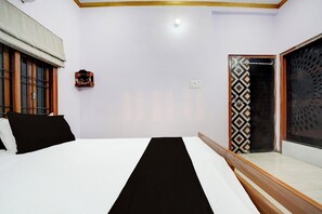 Une chambre à coucher avec un lit, une fenêtre avec des barreaux, un petit objet décoratif sur le mur et une porte ornée de carreaux à motifs.