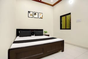 Un dormitorio con una cama, una mesita de noche, una planta en maceta y tres cuadros en la pared.