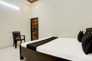 Ein Hotelzimmer mit einem Bett, einem Sessel, einem Wandbild und einem Fenster mit Gitterstäben.