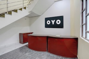 Un interior moderno con un escritorio de madera curvada, una escalera y un letrero en la pared con el texto 'OYO'.
