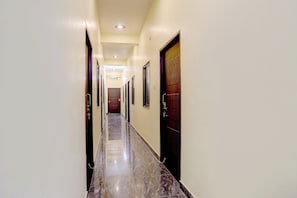 Un pasillo con puertas a ambos lados, piso de baldosas e iluminación empotrada en el techo.