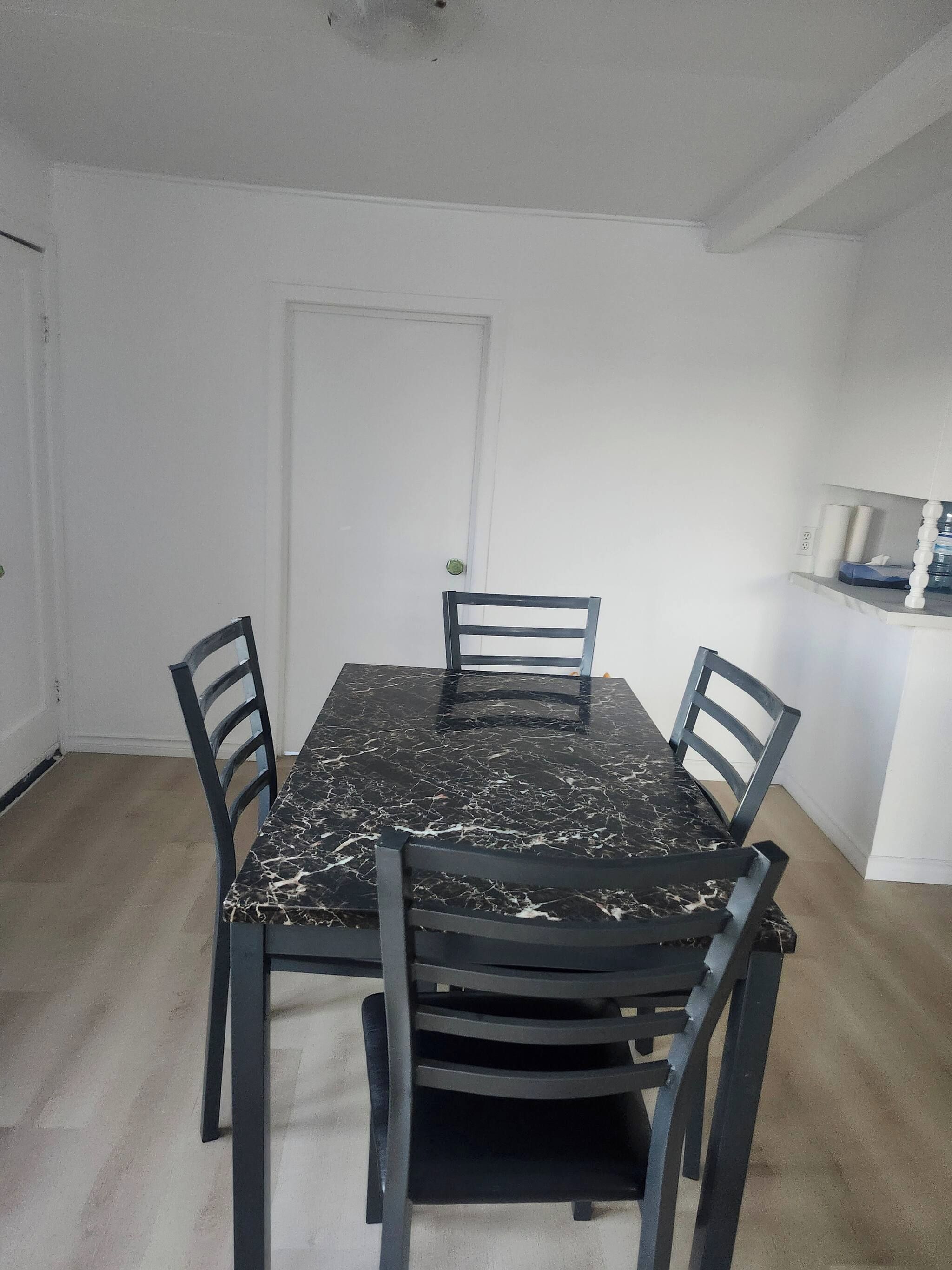 Un comedor con una mesa de mármol y cuatro sillas.