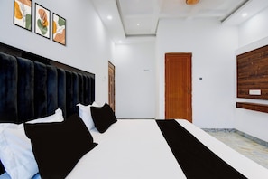 Une chambre d’hôtel avec un grand lit, une porte en bois et des œuvres d’art encadrées accrochées aux murs.