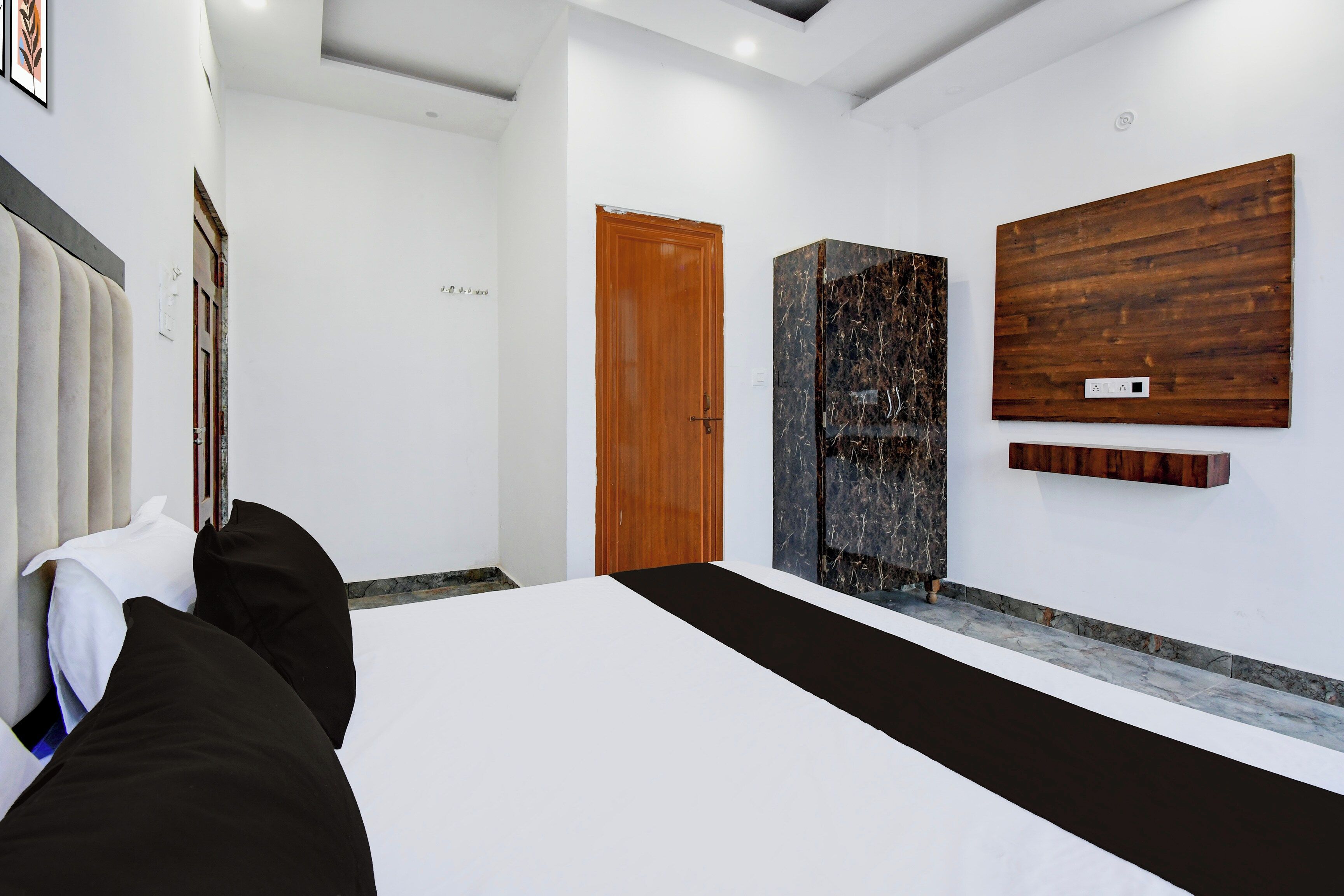 Une chambre d’hôtel avec un lit, une porte en bois et une grande œuvre d’art accrochée au mur.
